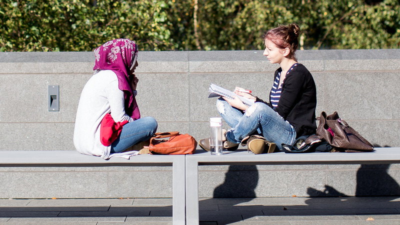 two students sitting on a bench talking